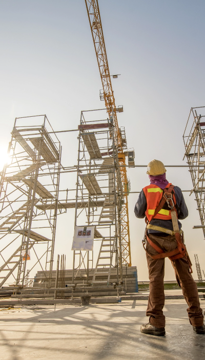 Construction engineers supervising progress of construction project stand on new concrete floor top roof and crane background