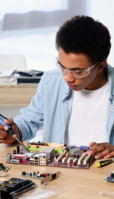 young student soldering computer circuit with soldering iron